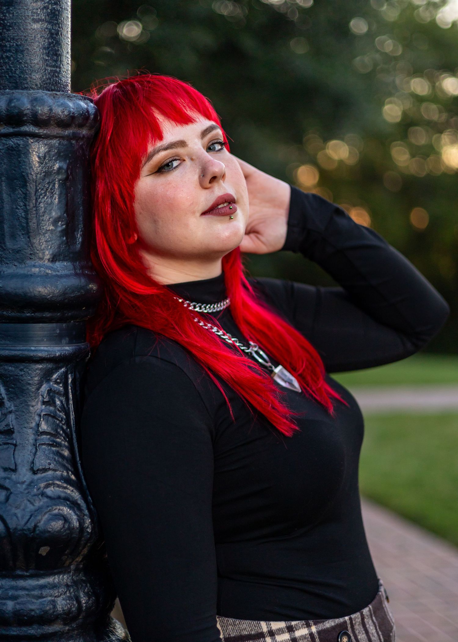 A dramatic pose against a black metal post features bold red styling and dark attire.