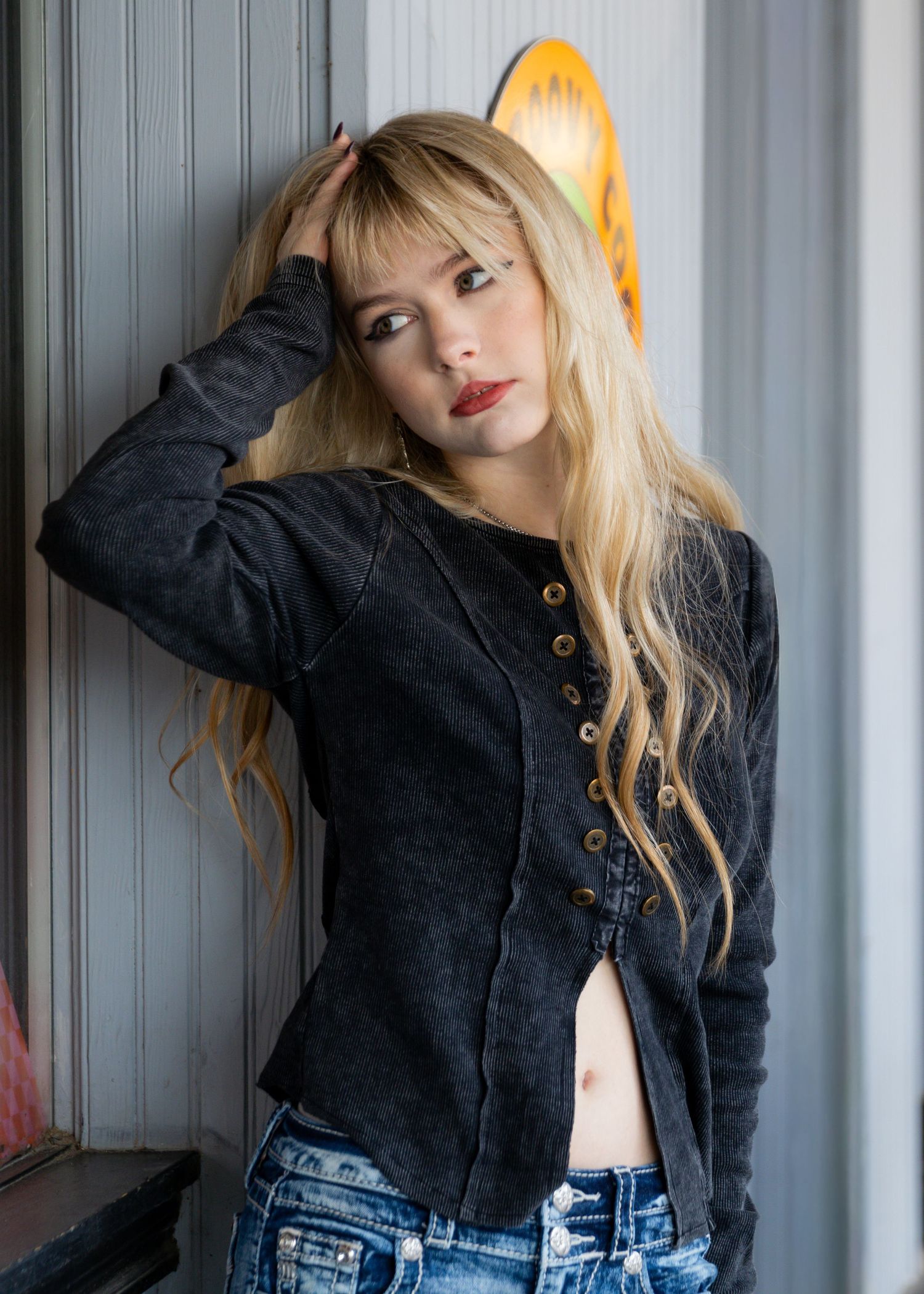 Fashion portraits against grey wall showing black cropped jacket and denim styling.