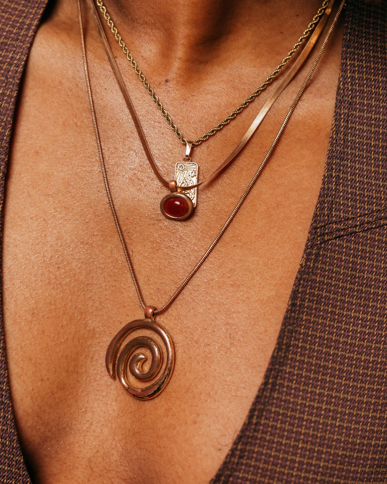 Collection of gold pendant necklaces displayed on brown surface.