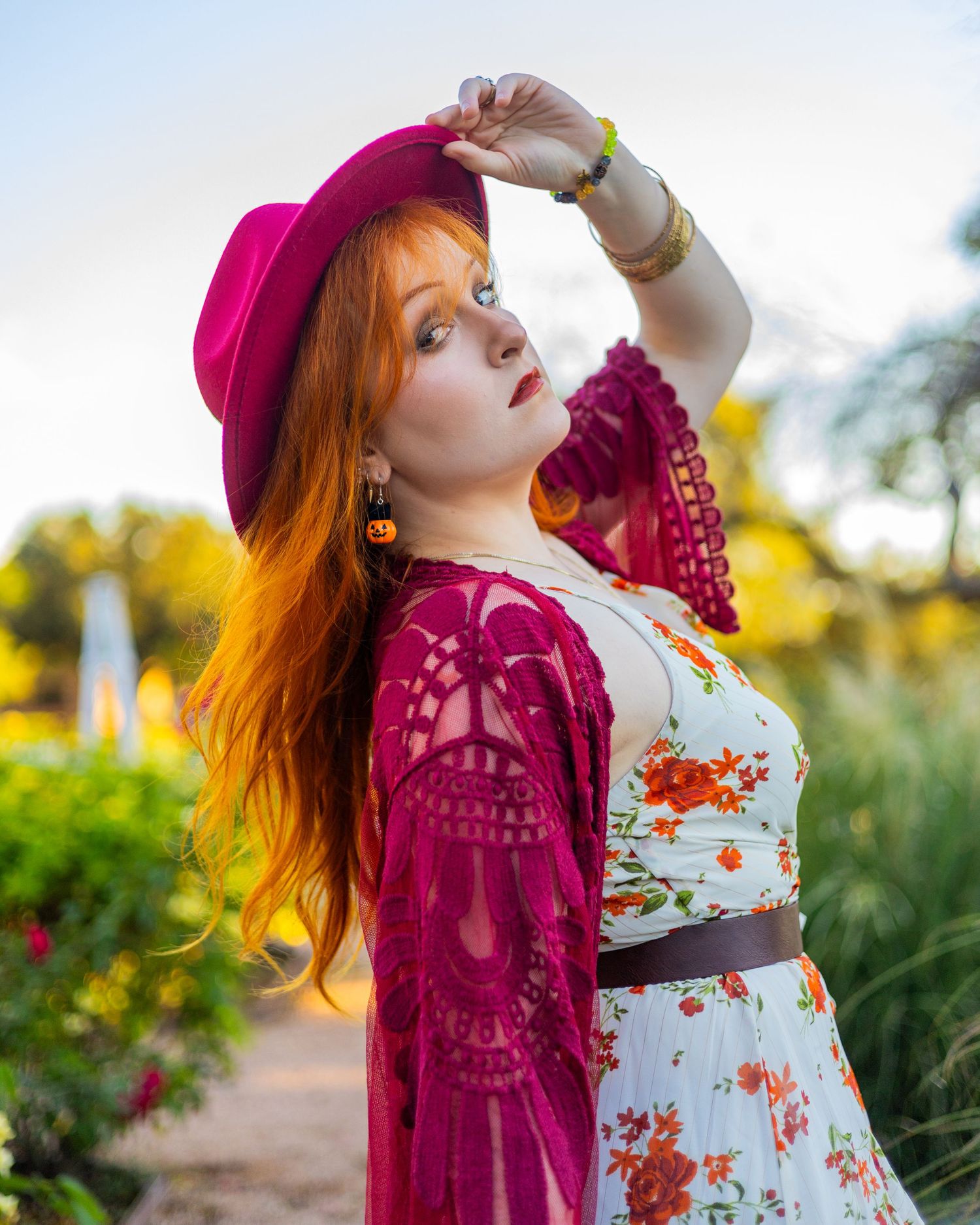 A floral dress paired with a burgundy lace shawl creates a romantic garden scene at sunset.