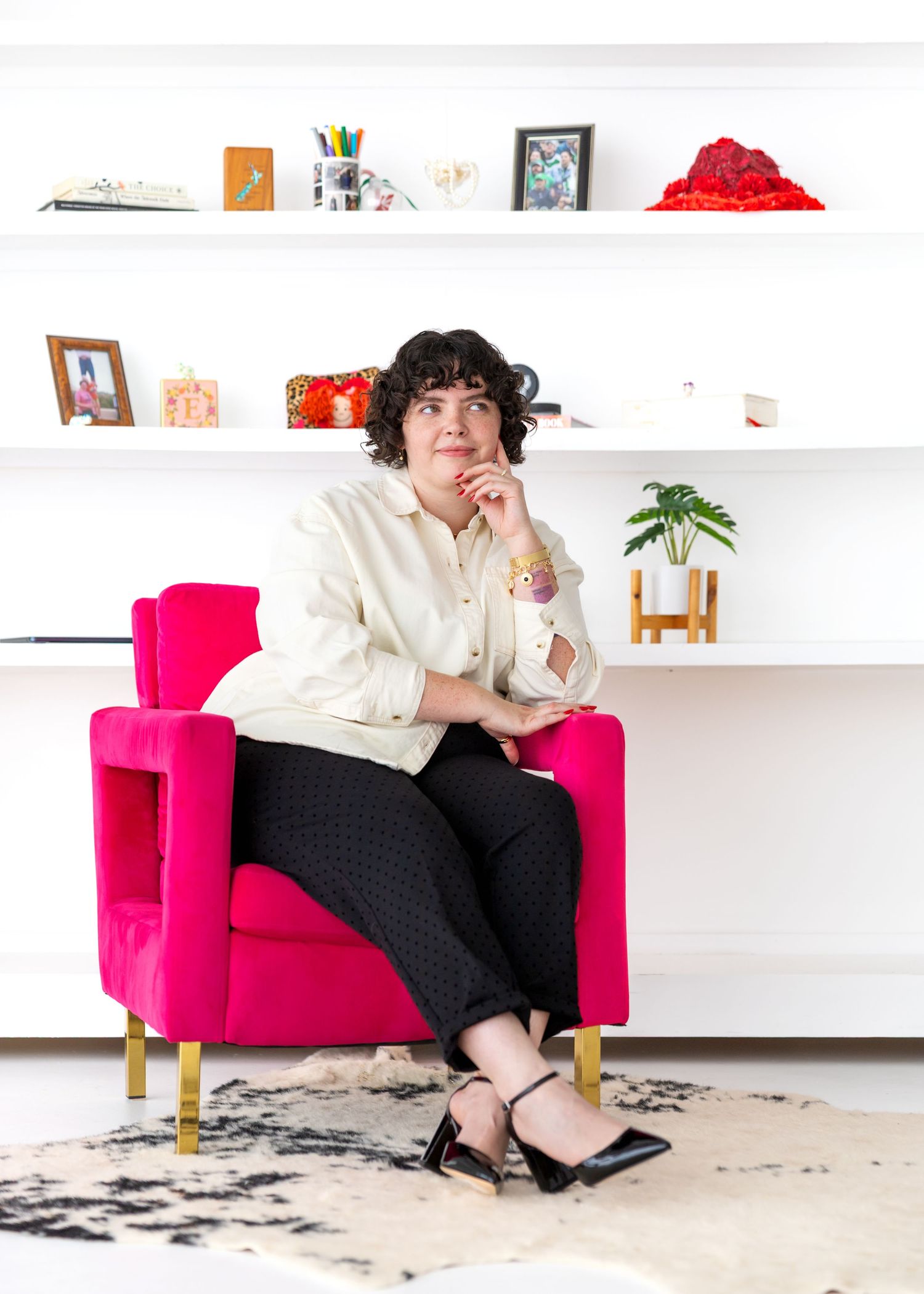 A series of images showing a person in a white top and black skirt sitting on a bright pink armchair against a white wall.