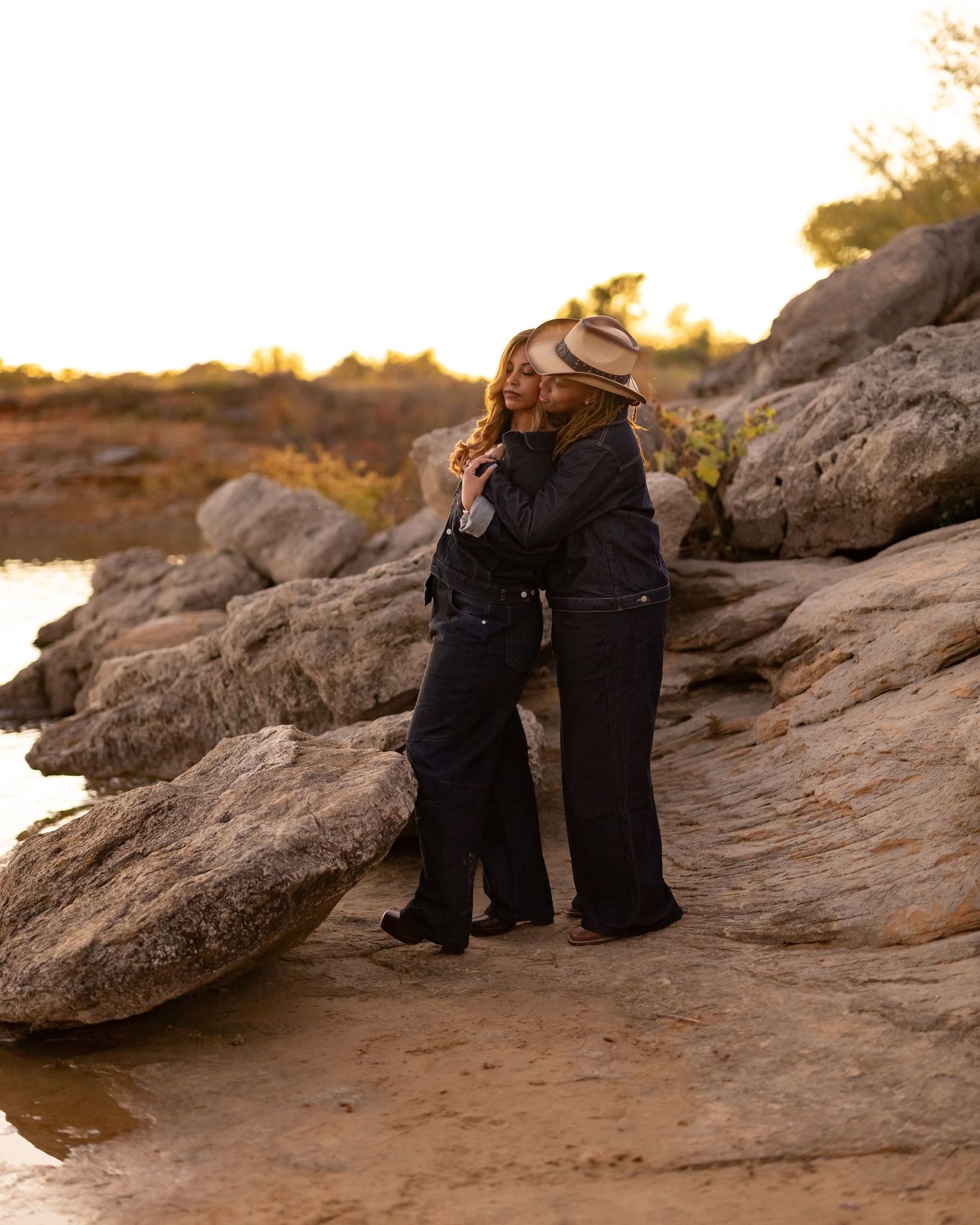 Couple sitting on rocky terrain during golden hour sunset.
