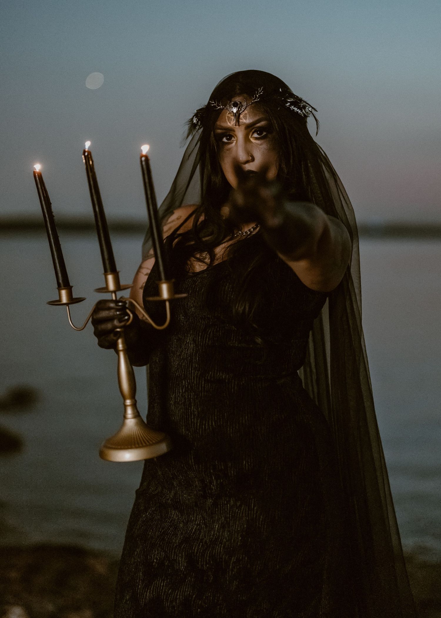A dark and moody series of photos showing a figure in black holding candelabras against a misty waterfront backdrop.