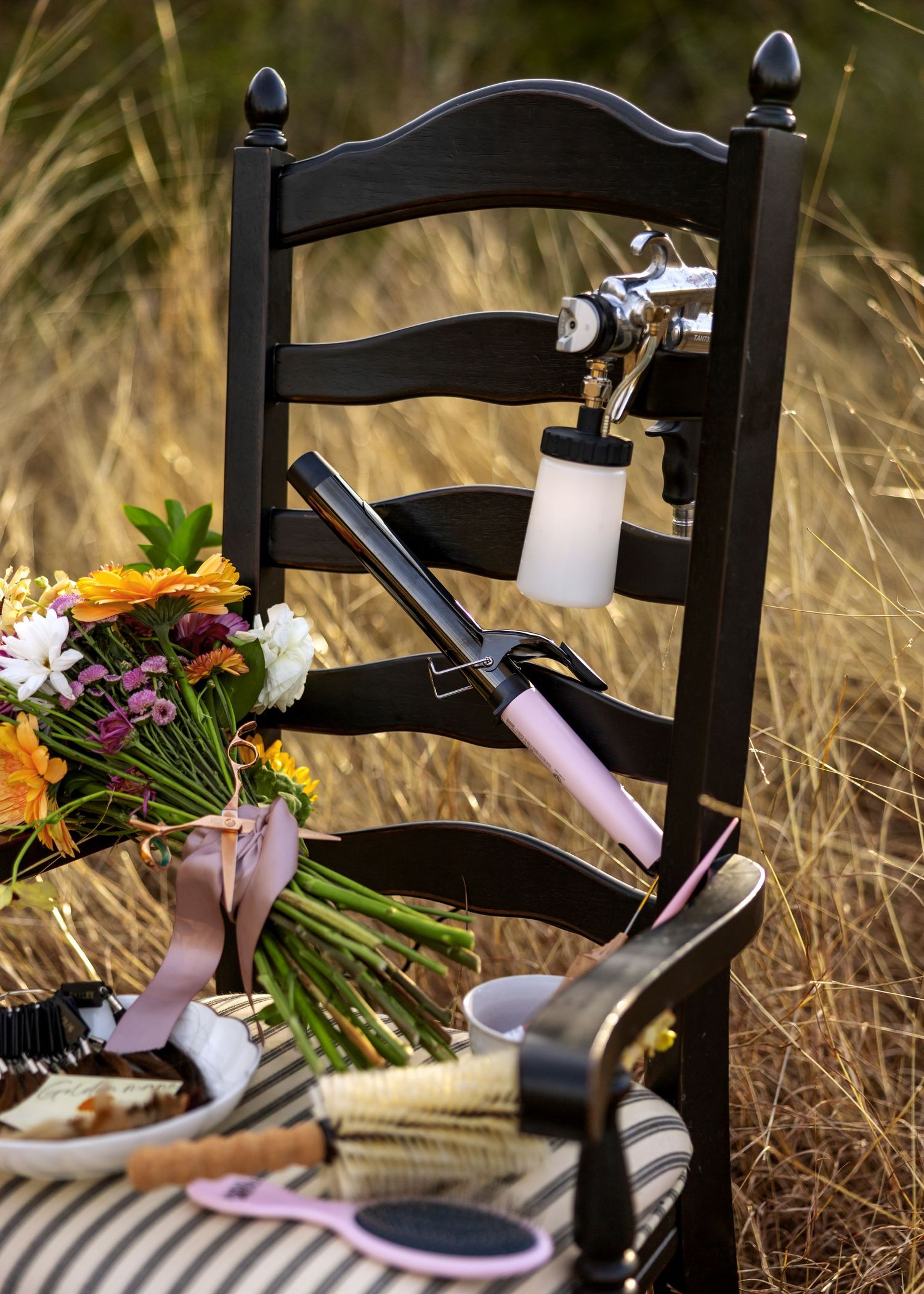 Black chair with striped cushion and floral arrangements in outdoor setting.