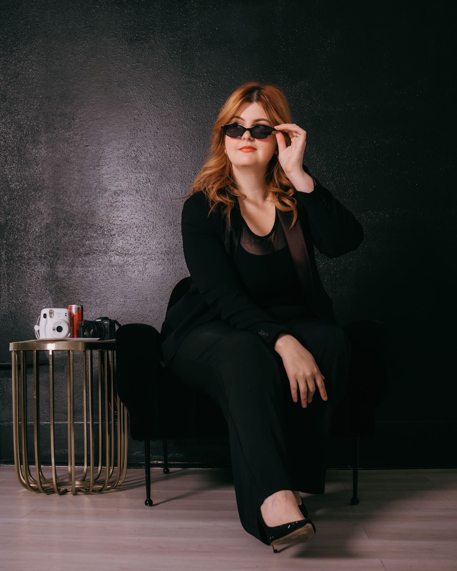 A moody fashion photoshoot series featuring a model in black attire against a dark backdrop with gold accents.