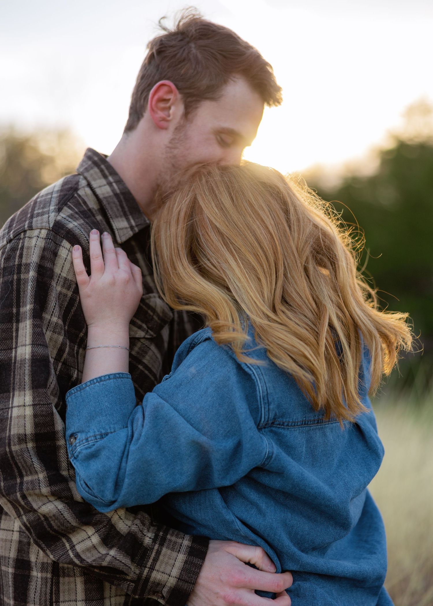 Intimate moment between couple in casual wear during sunset photoshoot.