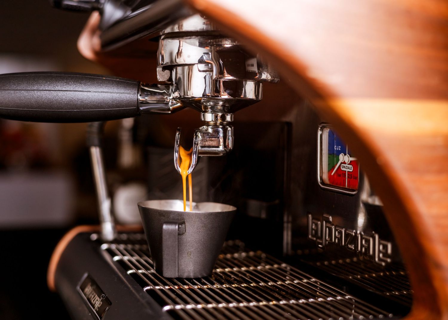 Close-up shot of espresso machine extracting coffee into a small cup.