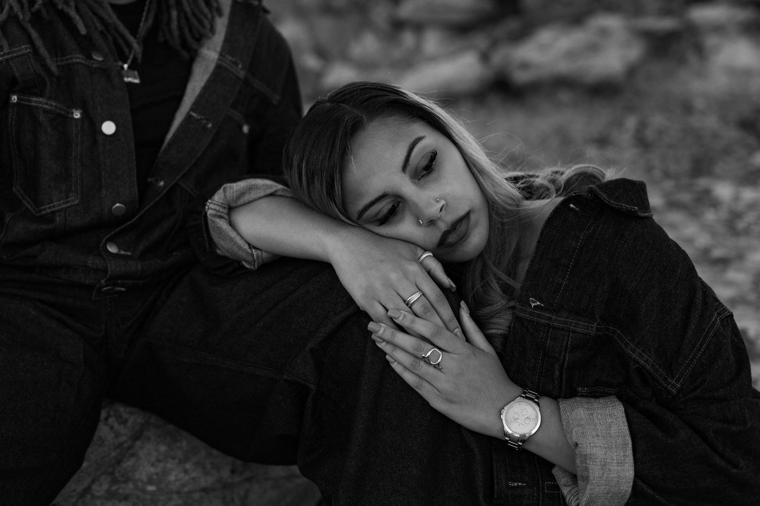 Black and white portrait of couple in intimate poses on rocky landscape.