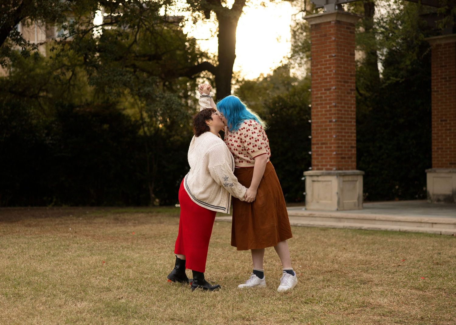 A couple in vintage-inspired outfits walking through a garden path with autumn foliage.