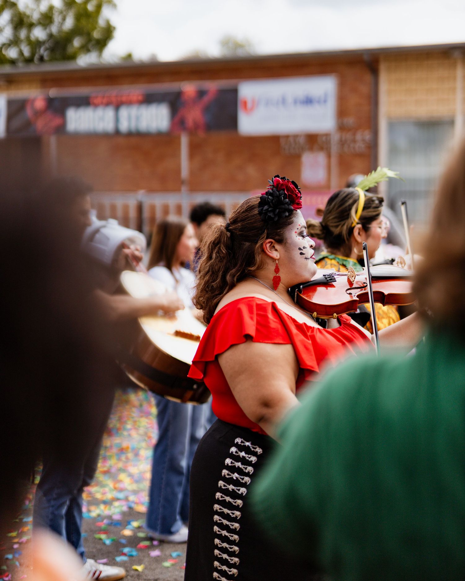 People in red outfits gather at an outdoor event with confetti scattered around them.