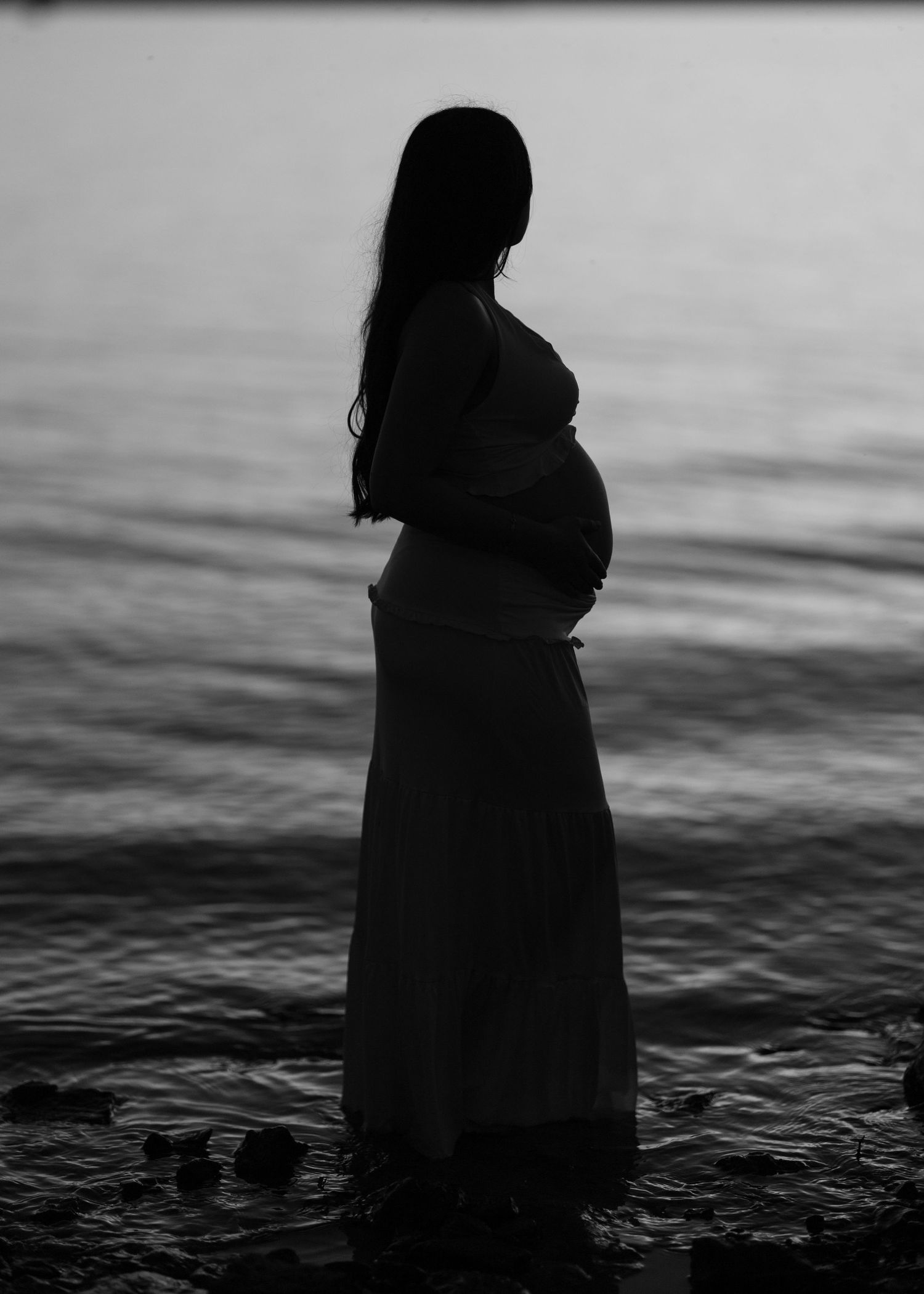 Black and white silhouette of a figure standing by water.