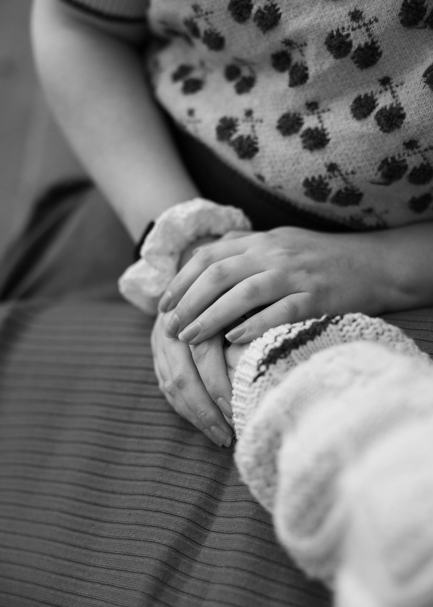 Close-up black and white shot of hands gently touching polka dot fabric.