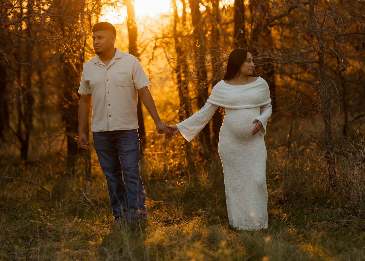 Silhouetted figures stand together in a wooded area during golden hour.