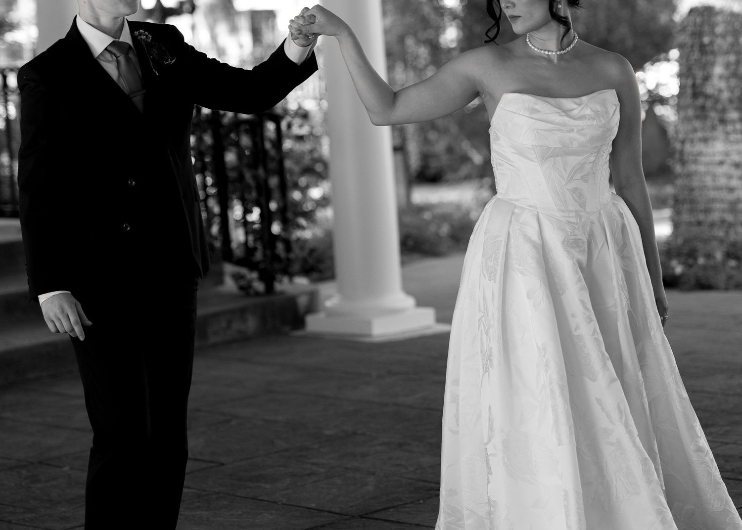 Black and white photo of a bride and groom dancing together outdoors at their wedding reception.
