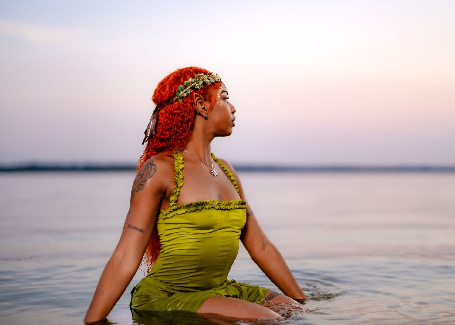 A woman in a chartreuse dress poses gracefully along a serene beach at sunset.