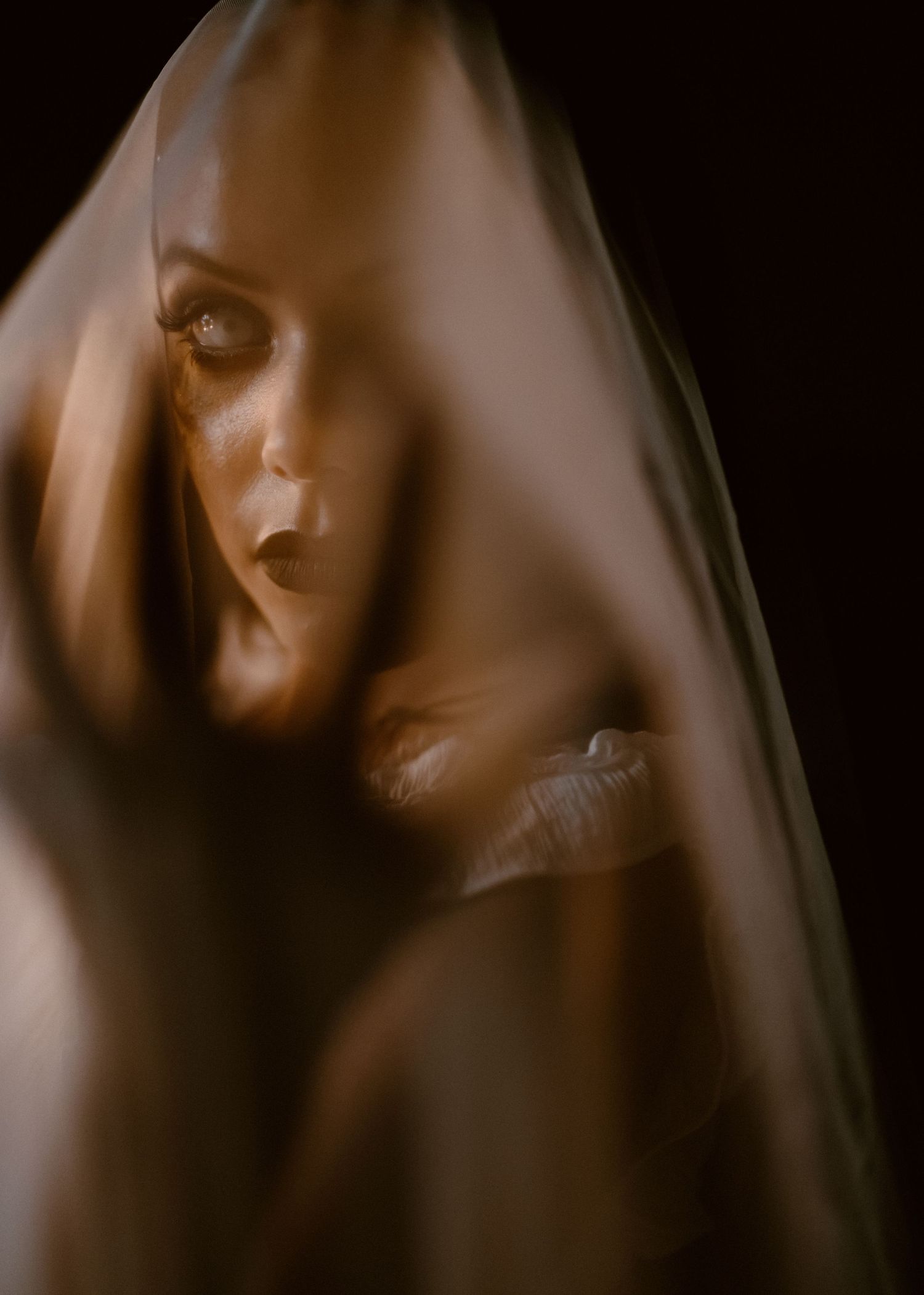 Moody close-up portraits through sheer fabric creating an ethereal effect.