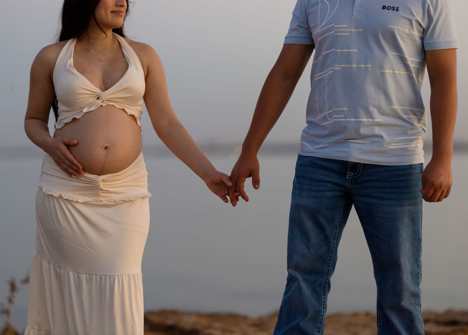 Casual outdoor photoshoot on rocky beach during sunset.