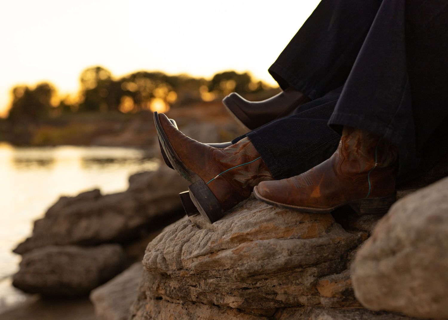 Boots and silhouettes visible against rocky terrain during sunset photoshoot.