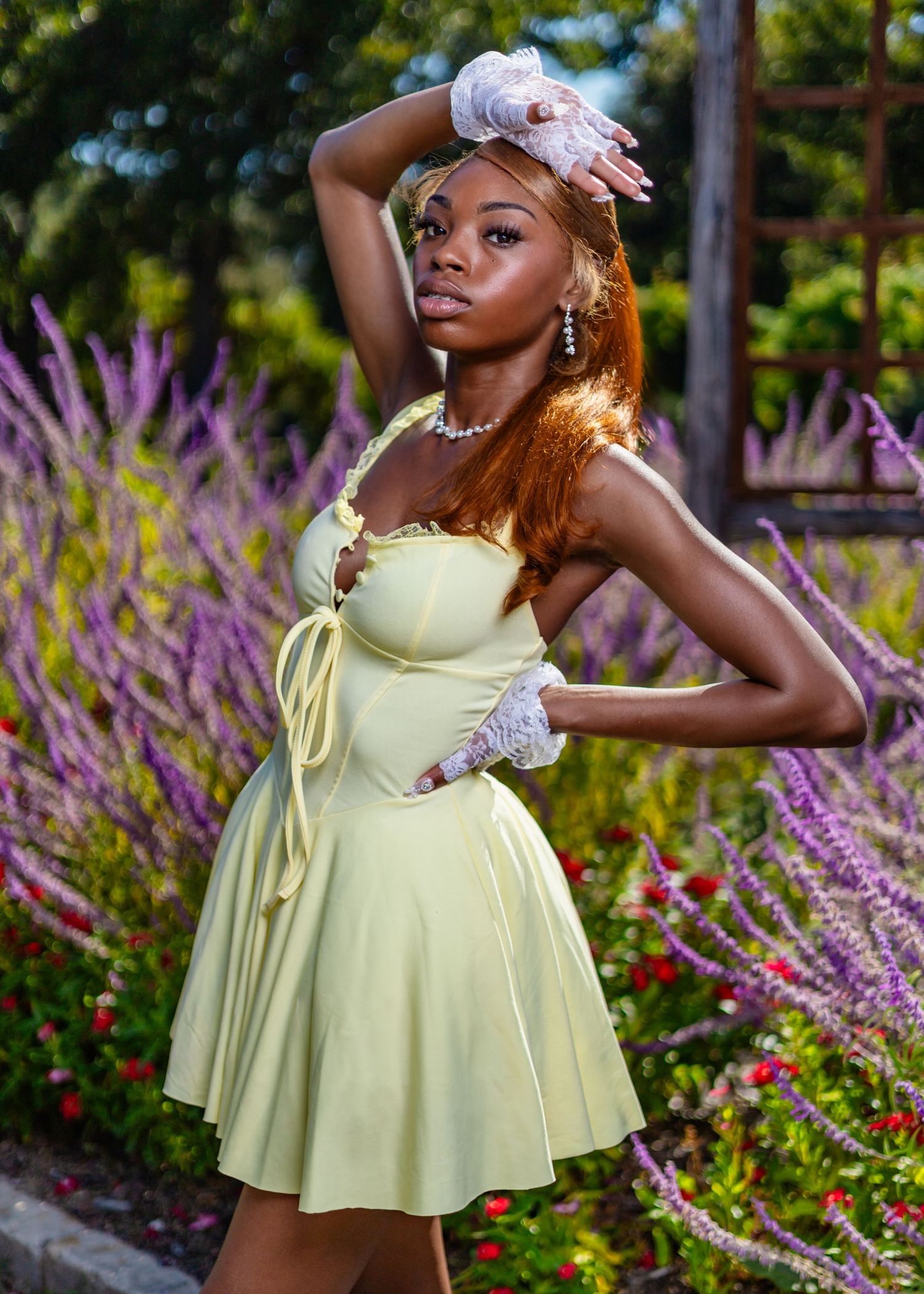 Vintage-inspired garden portrait in pale yellow dress with lace accessories among purple flowers.