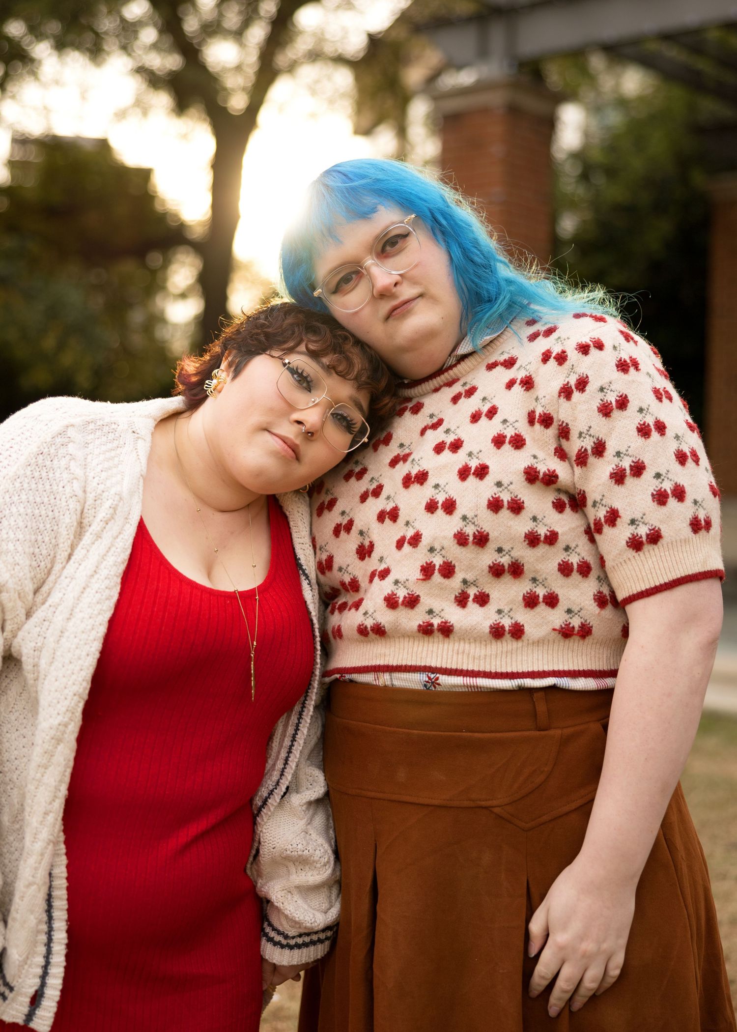 Two people resting heads together while sitting on wooden bench.