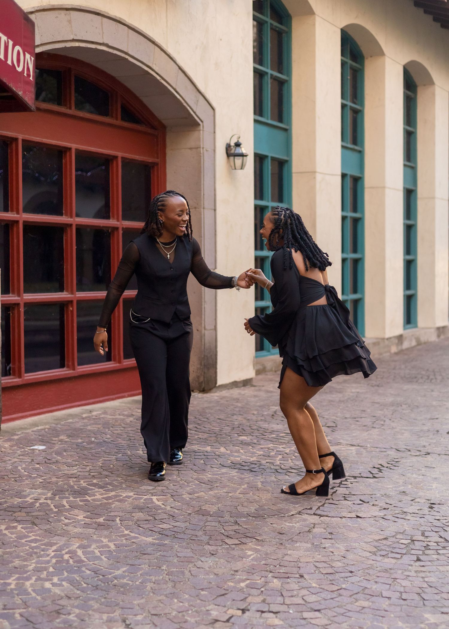 A dancer performs a graceful sequence of dance moves on a cobblestone floor in front of an arched building facade.