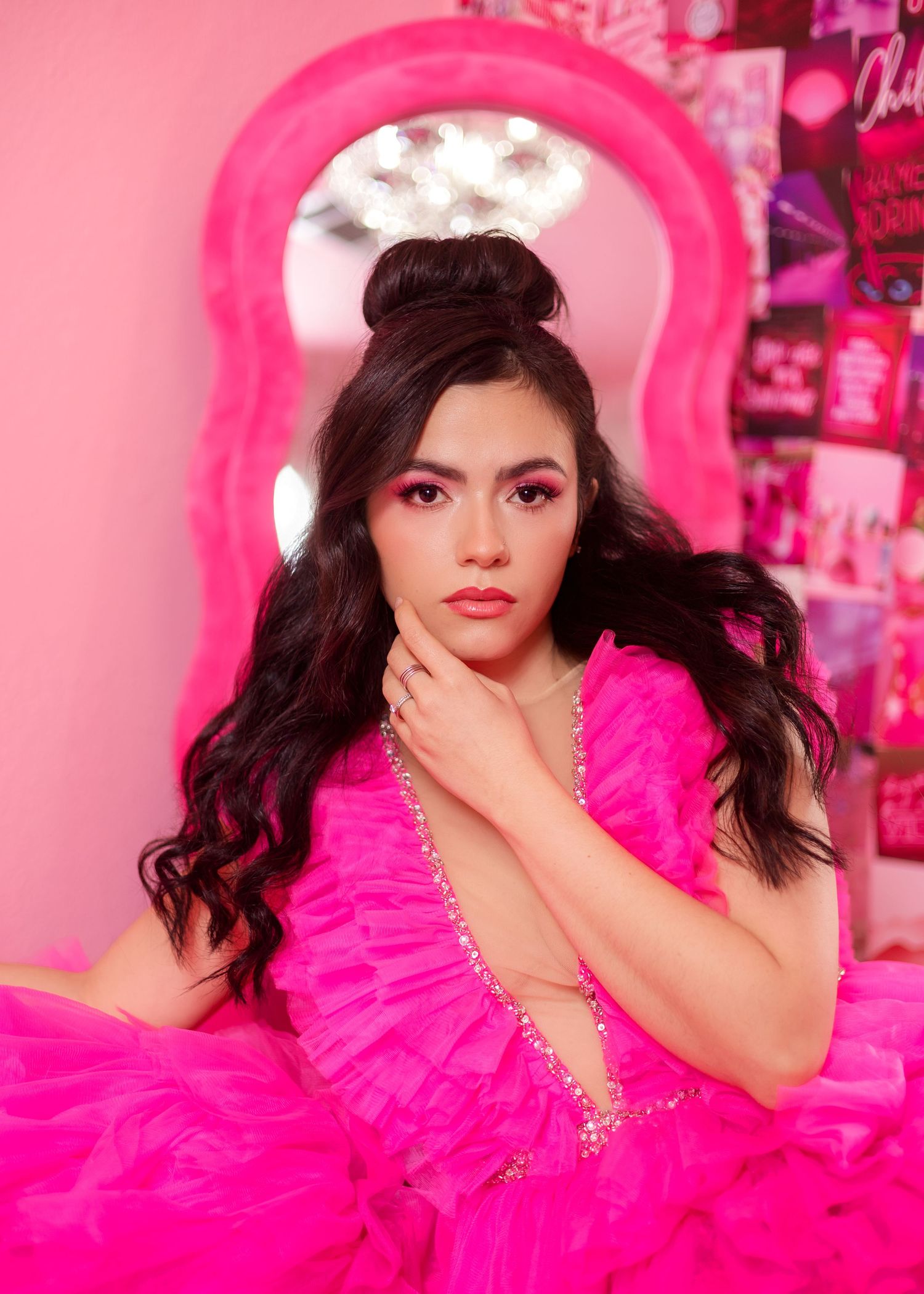 A vibrant pink tulle dress creates a dramatic silhouette against a pink-themed backdrop with wall decor.