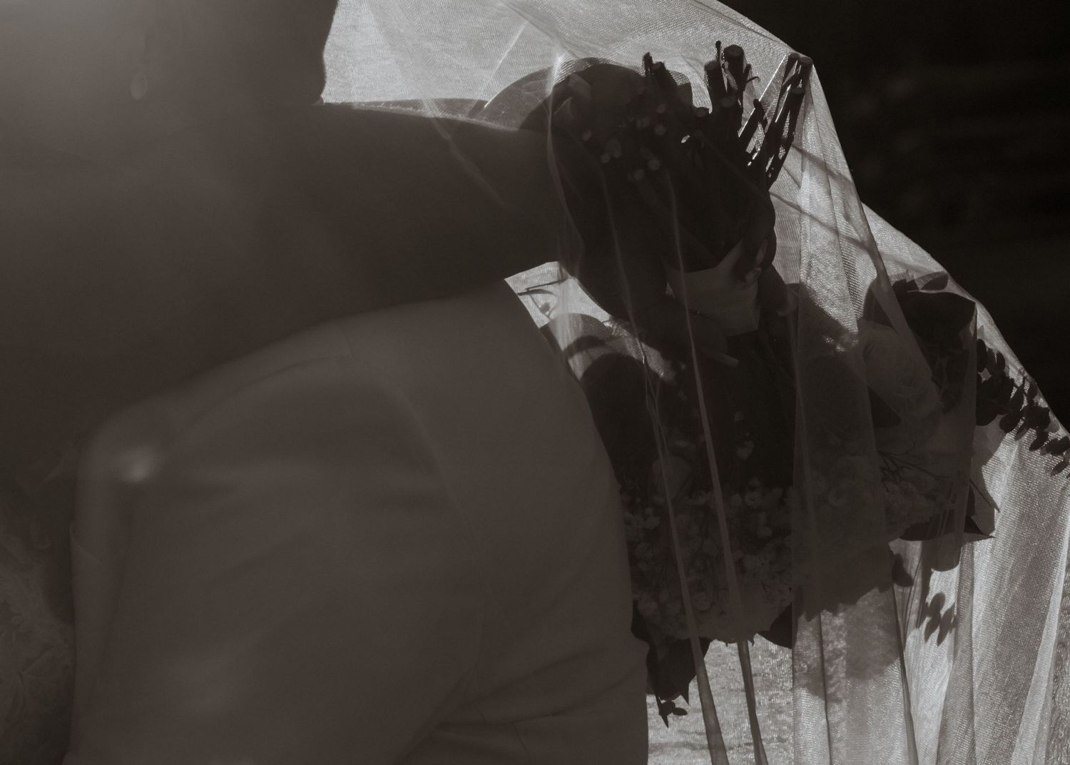 Black and white photo of a bride in a veil with dramatic lighting and shadows.