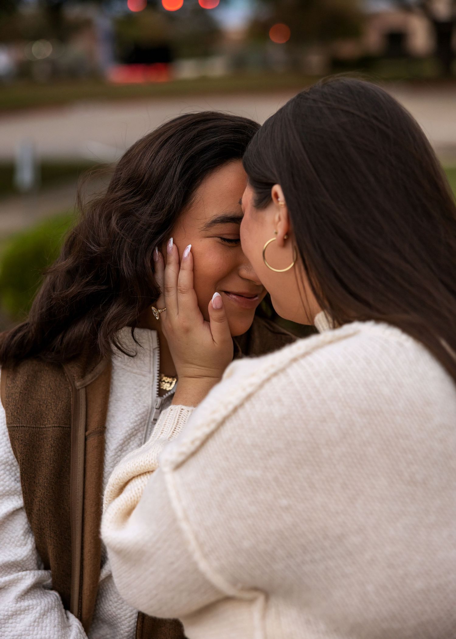 Two people share an intimate moment in white sweaters against a dark background.