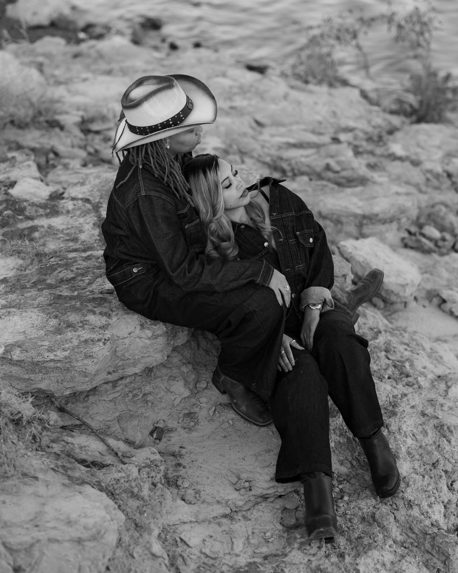 Black and white images of couple in western wear lounging on textured rock formation.