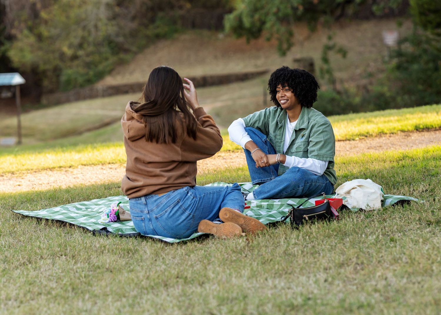People relaxing on picnic blankets spread out on grass in a park setting.