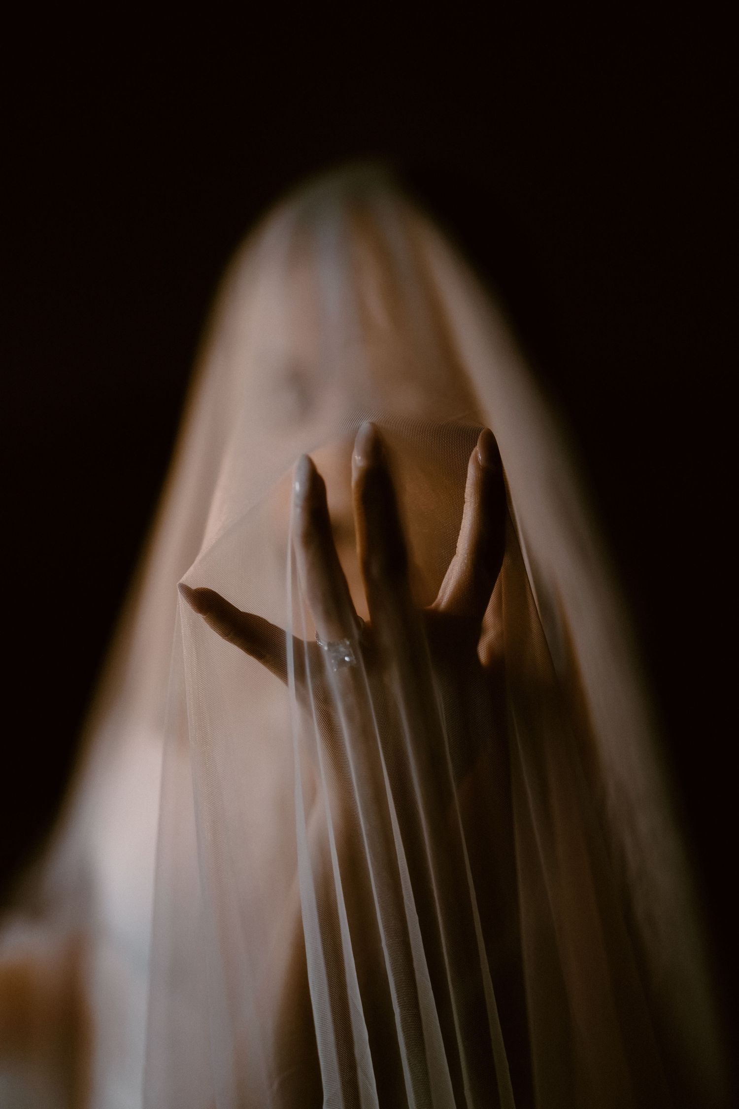 Haunting artistic portrait series showing hands through translucent white fabric in dim lighting.