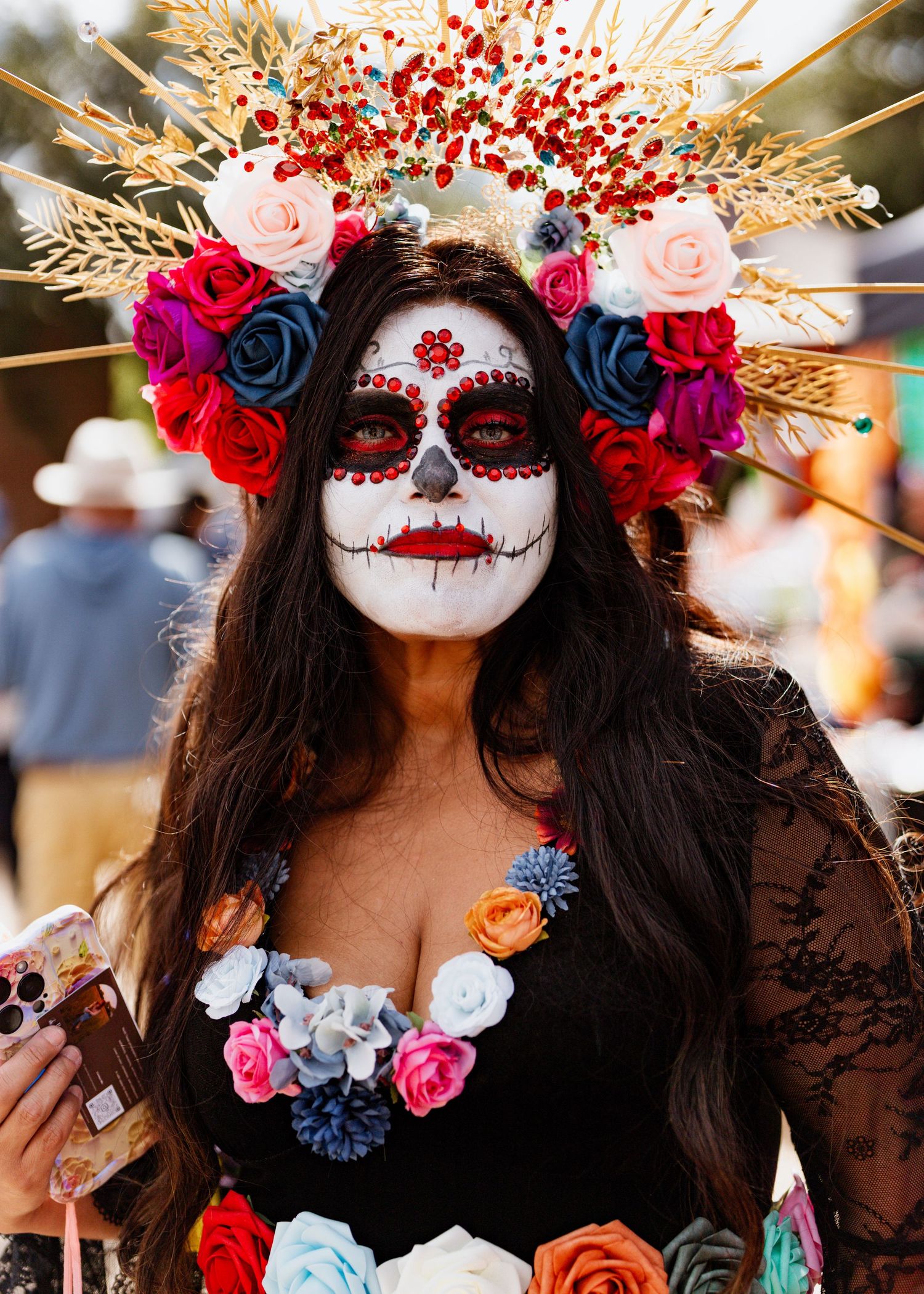 Day of the Dead sugar skull makeup with colorful roses and gold wheat crown in traditional Mexican style.