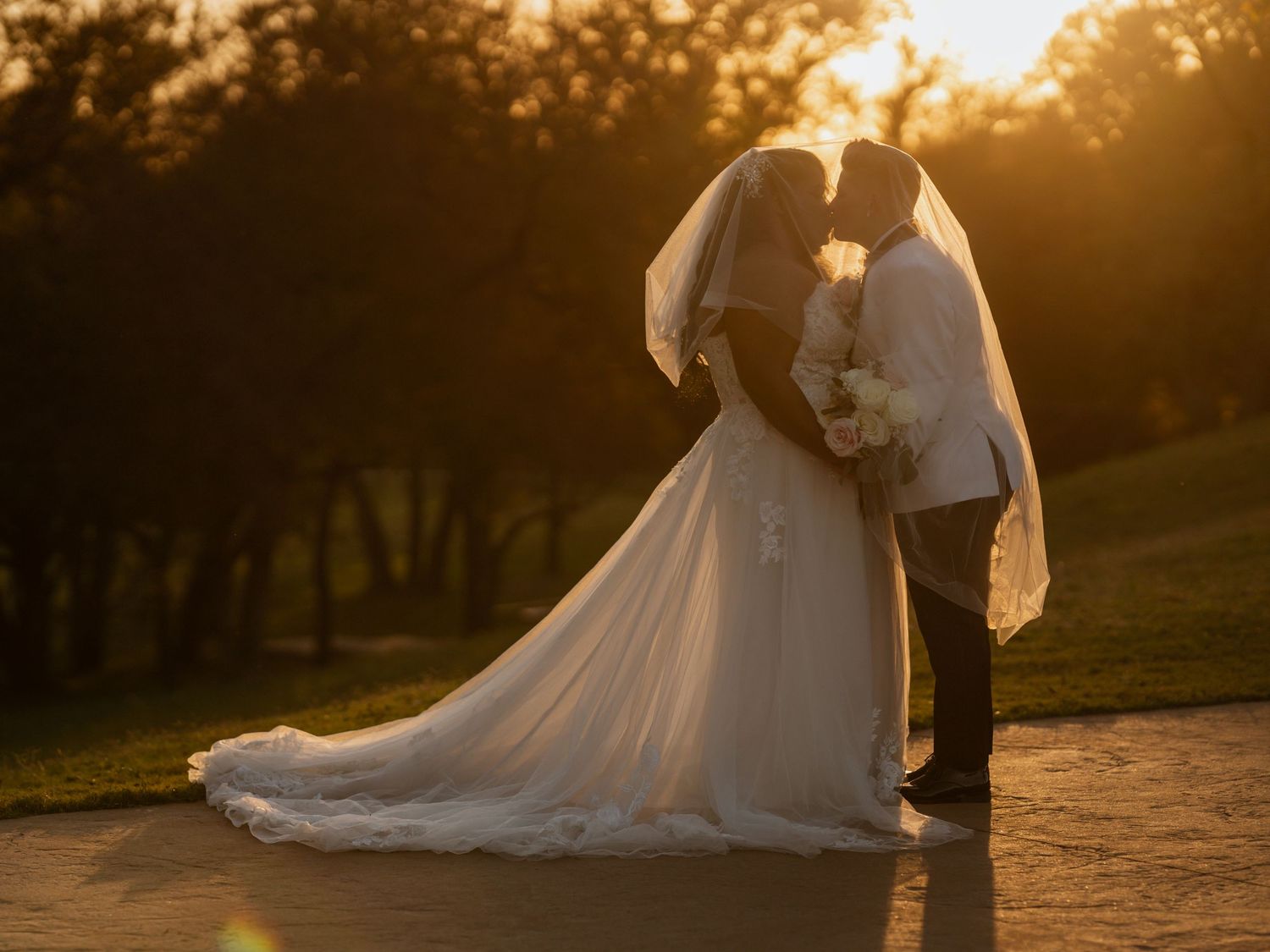 Romantic sunset wedding photos on grassy hillside.