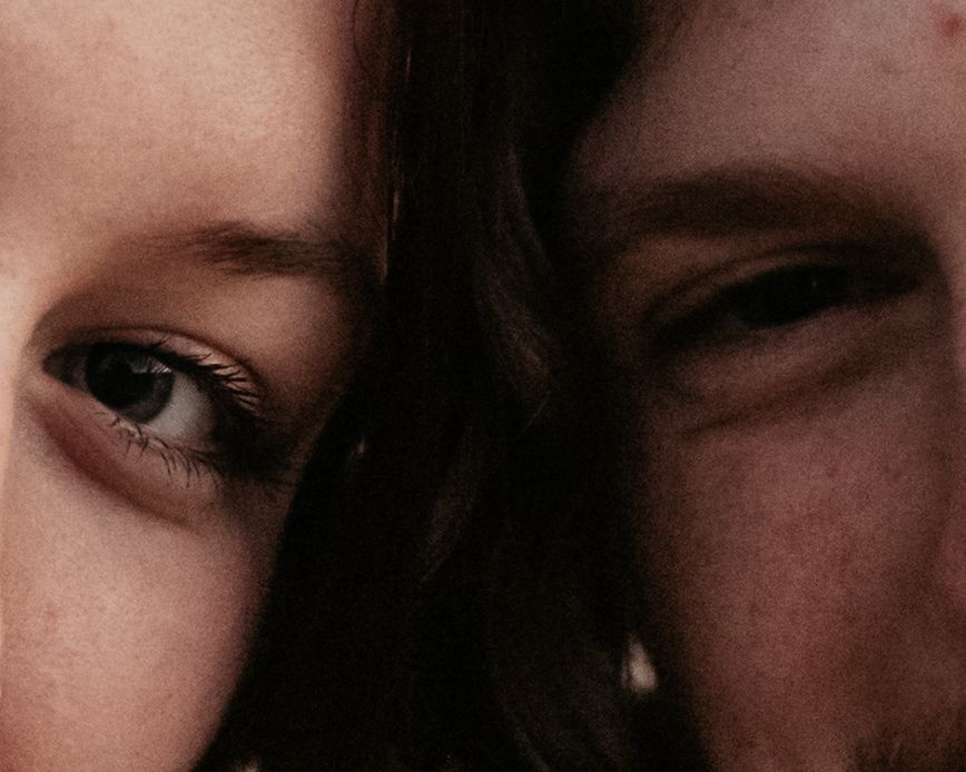 Artistic close-up portrait showing half faces in warm lighting.