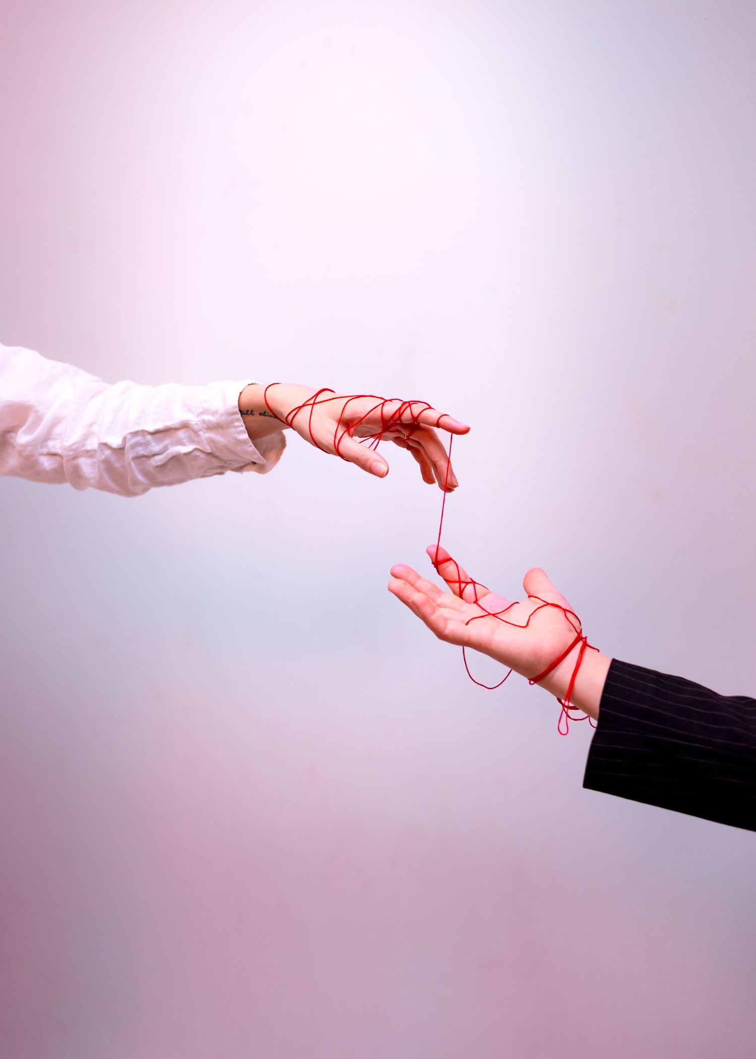 A sequence of five images showing hands in white and black gloves connected by a flowing red string or thread.