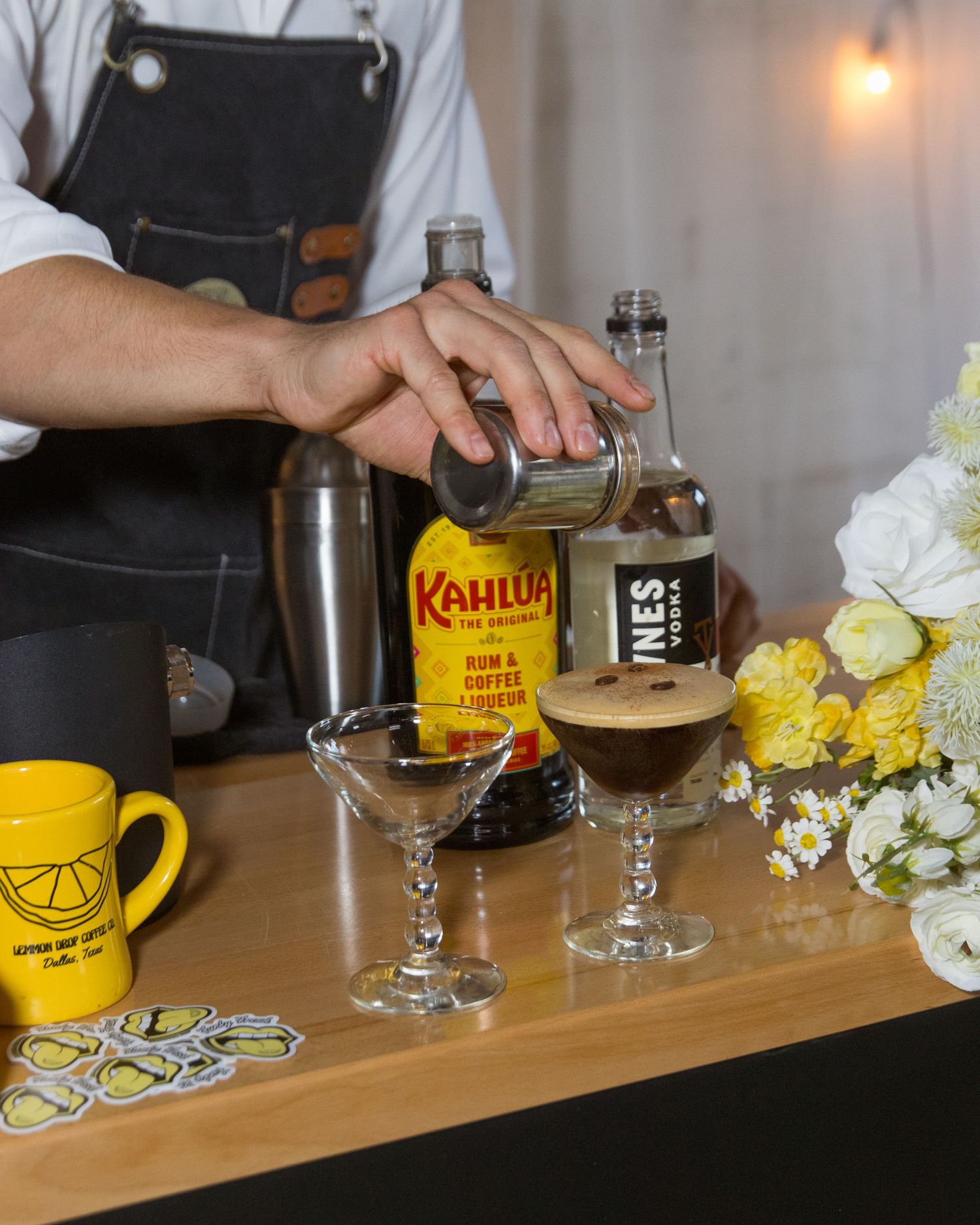 Bar setup with Kahlua bottles, yellow mugs, and floral decorations.