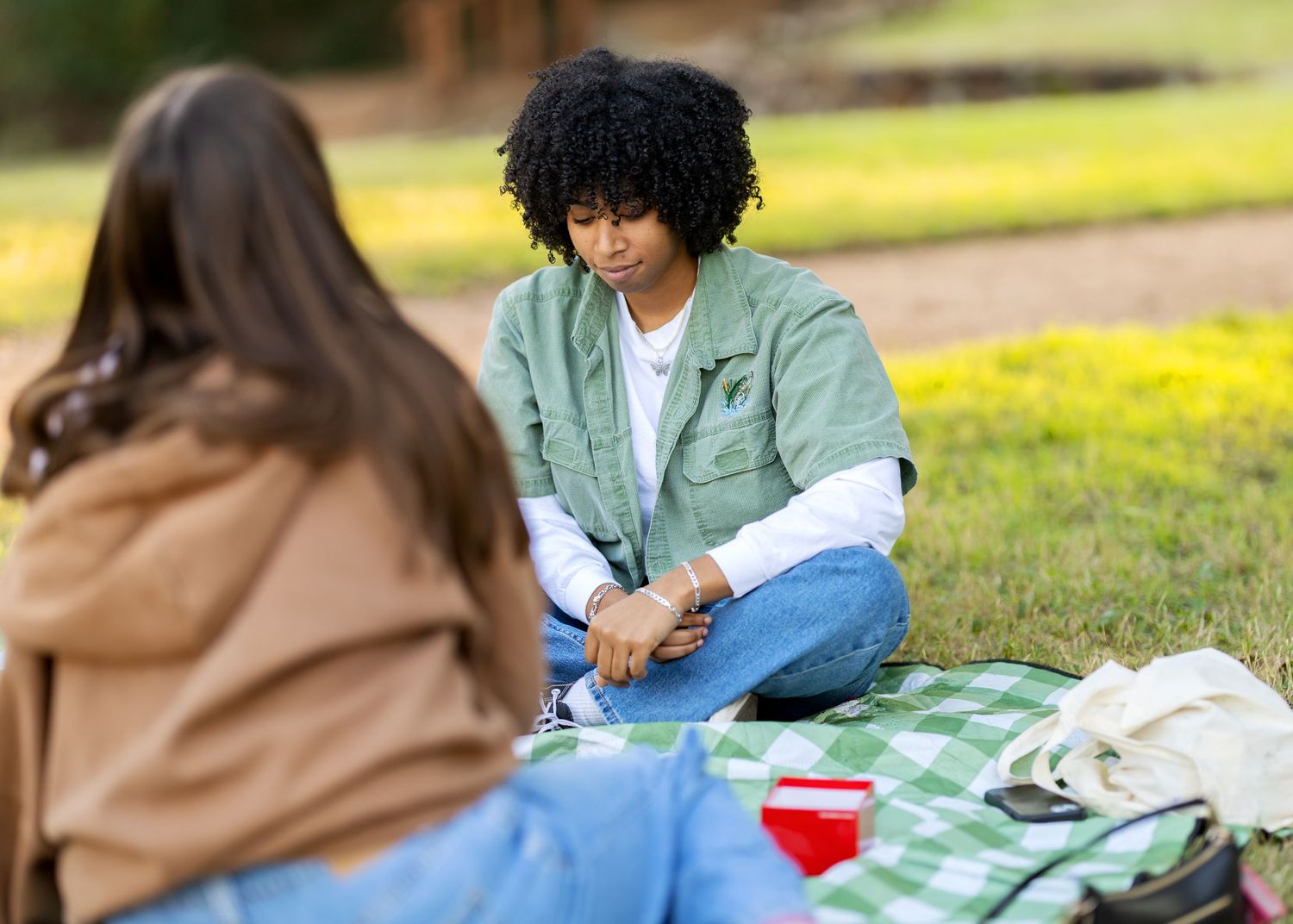 Casual outdoor gathering on blankets with people in relaxed poses.