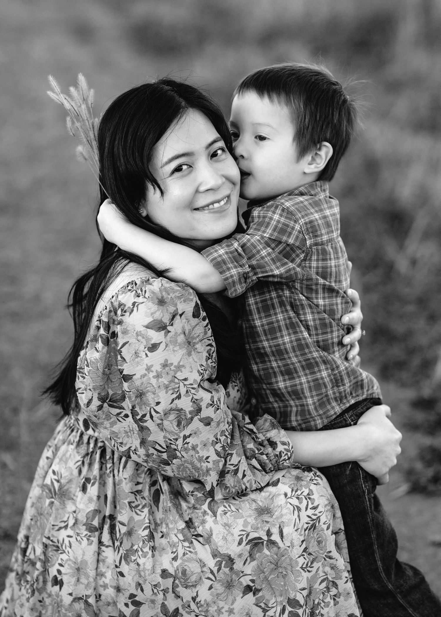 A mother and young child share tender moments in black and white photos wearing floral dress and plaid shirt.