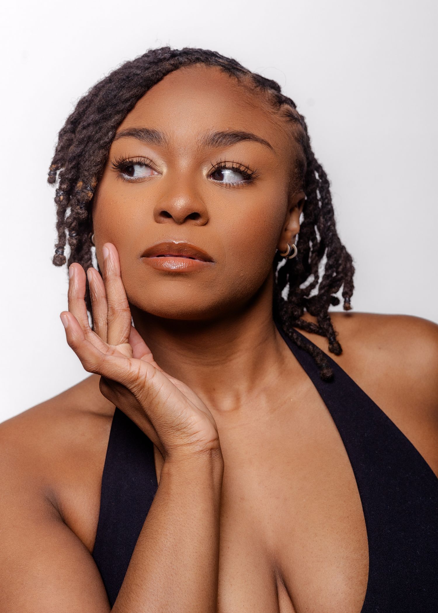 Close up beauty portrait in black halter top against white background with elegant pose.