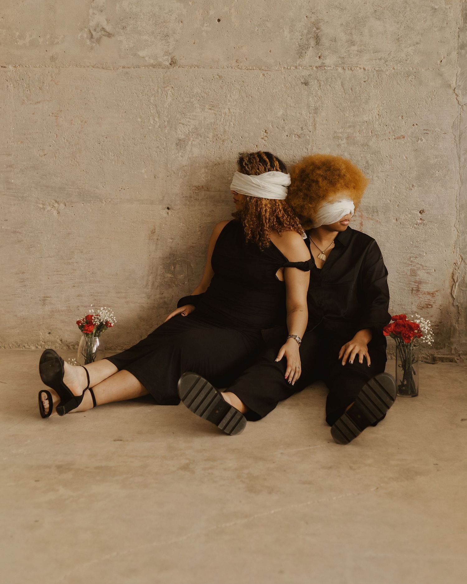 A series of artistic photos showing two people lying on a concrete floor in various poses with red flowers nearby.