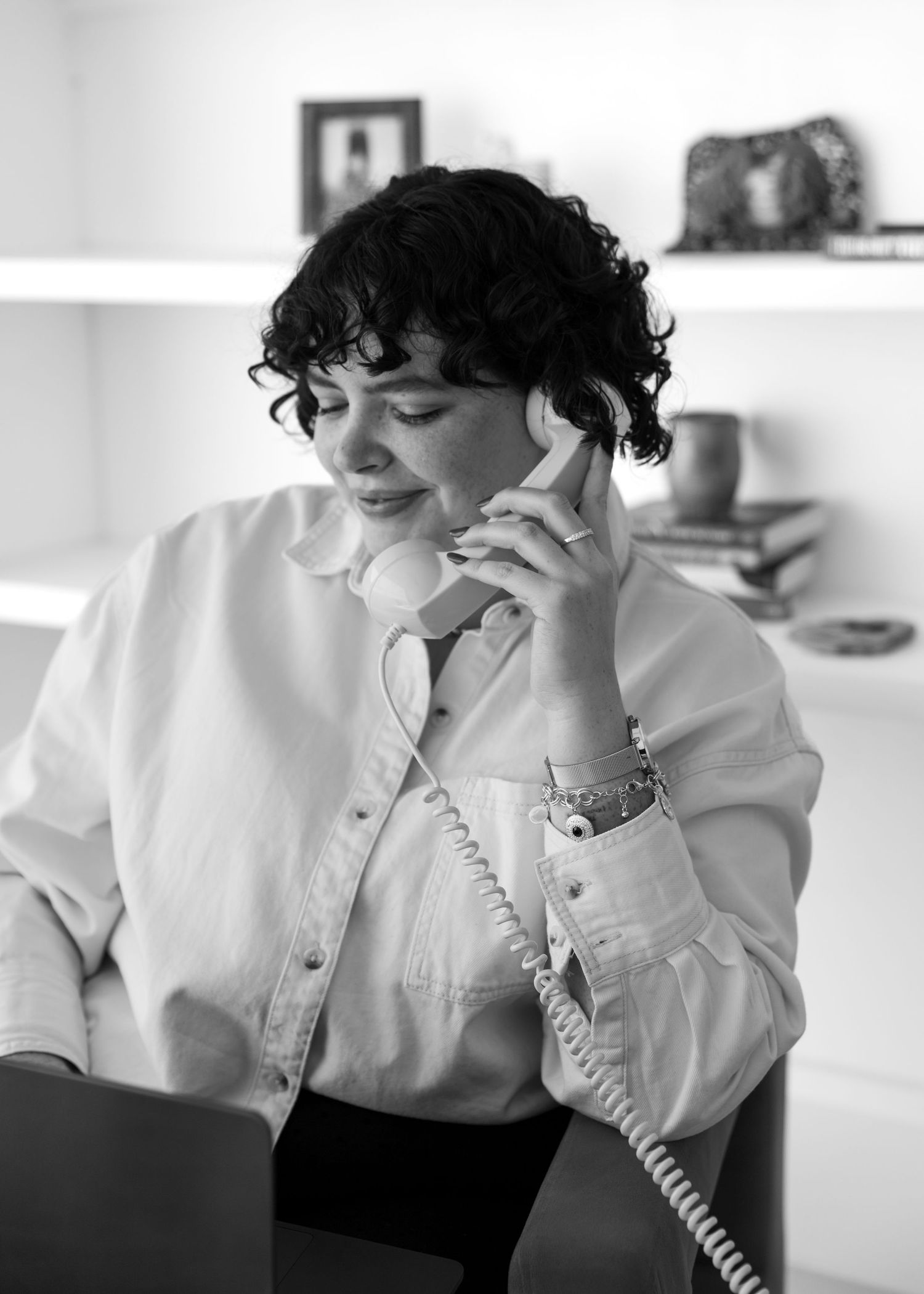 A black and white sequence of four photos showing someone in a white shirt talking on a vintage telephone.