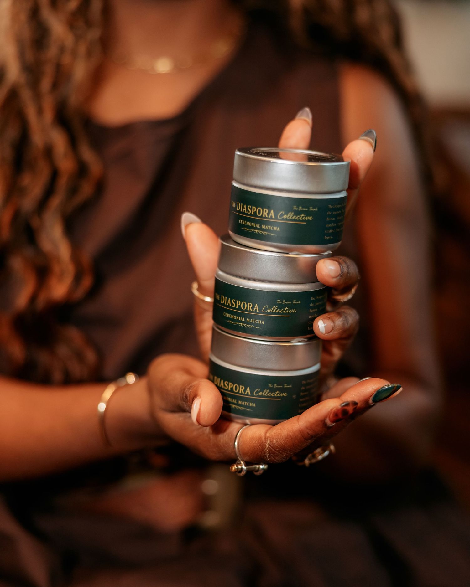 Hands holding stacked green product containers in dim lighting.