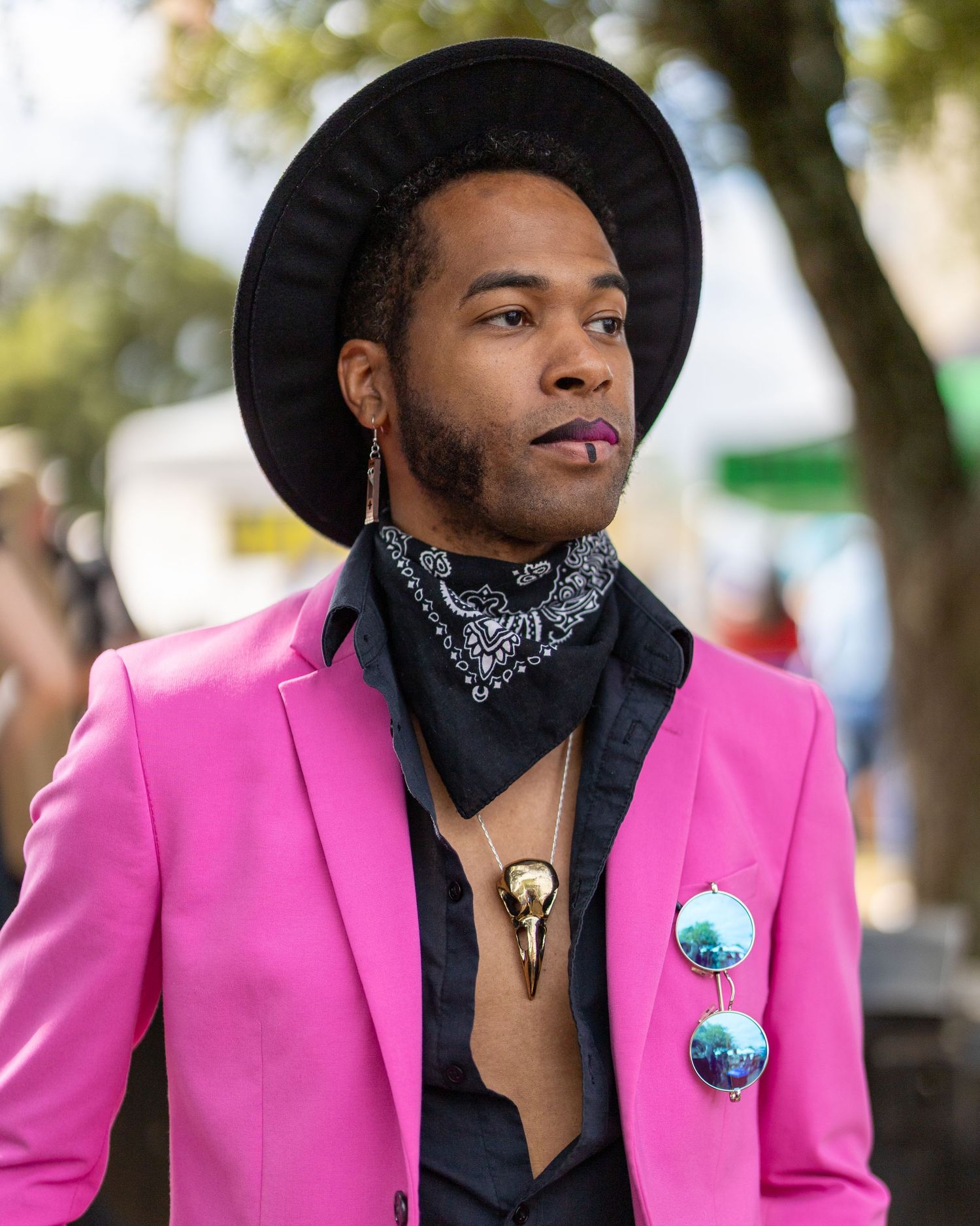 A stylish pink blazer outfit with black accents and a circular pin accessory creates a bold fashion statement.