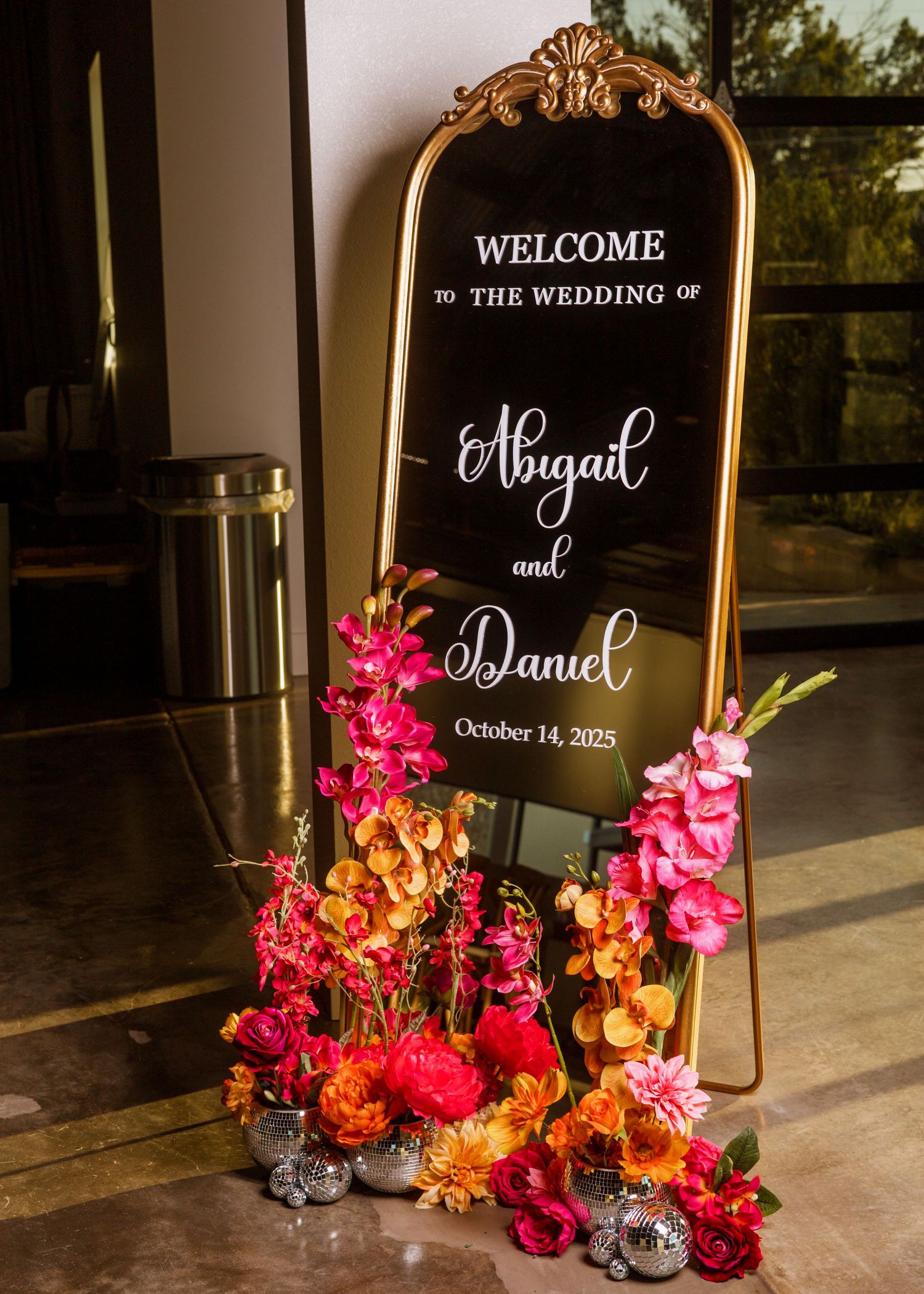 Gold mirror wedding welcome sign for Abigail and Daniel, October 14 2025, with vibrant floral arrangements.