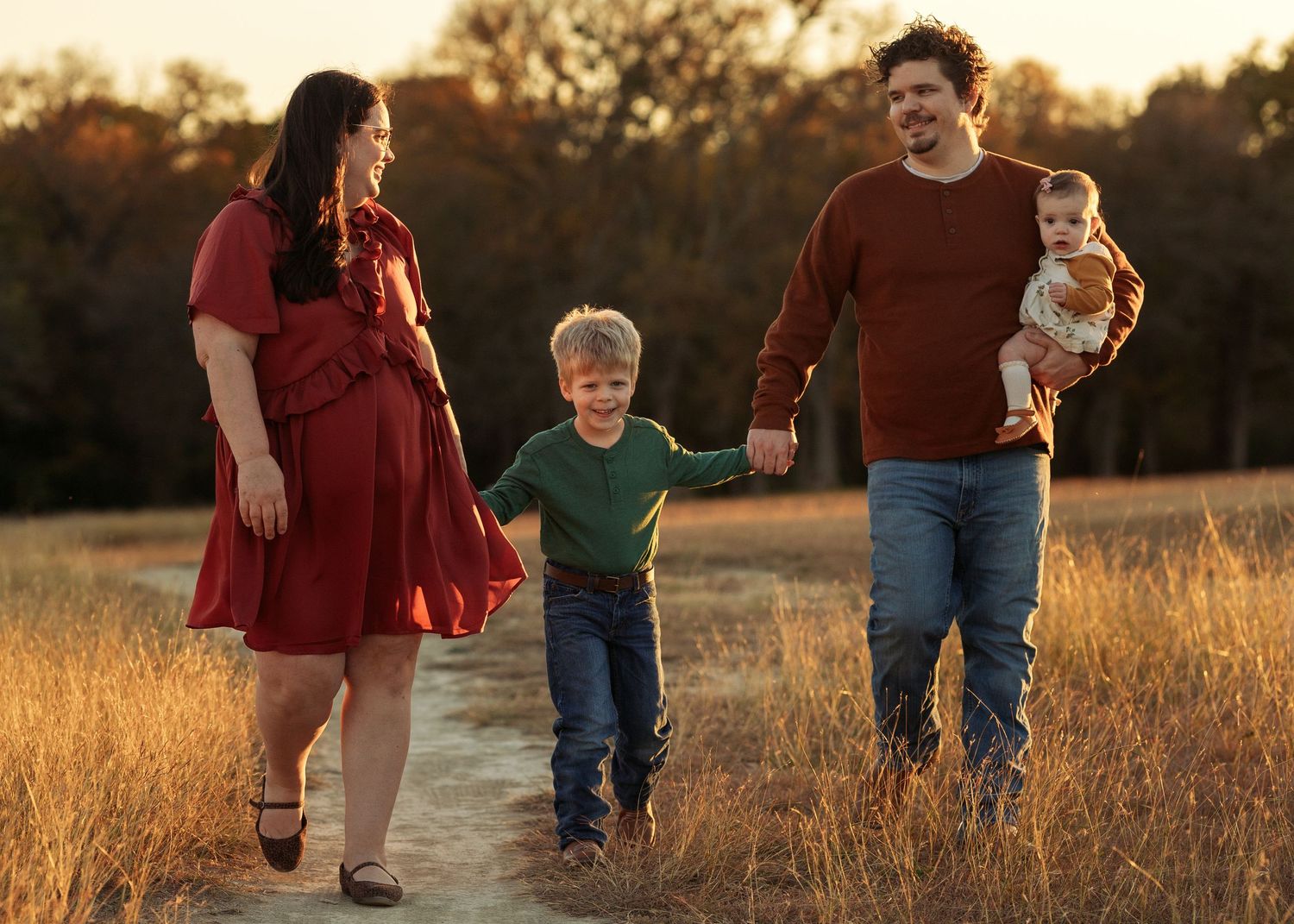 Family walking together through autumn field at golden hour.