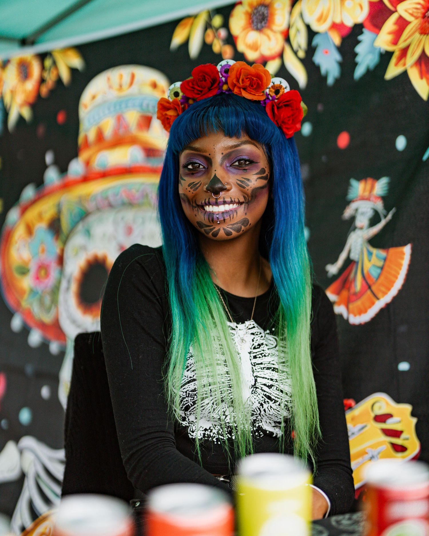 Colorful festival scene with face-painted attendee wearing bright blue hair and floral crown.