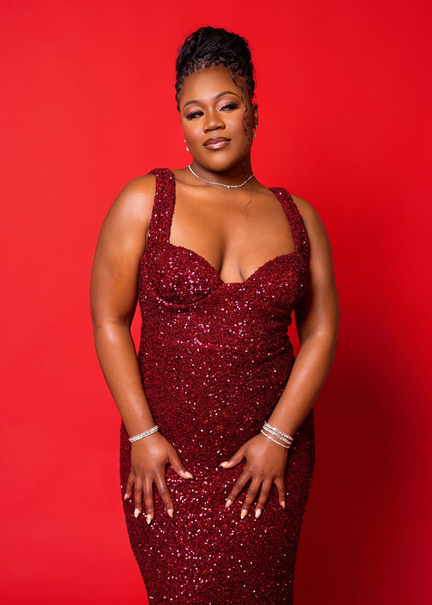 A glamorous fashion shoot against a bold red background showcasing a glittering deep red evening gown.