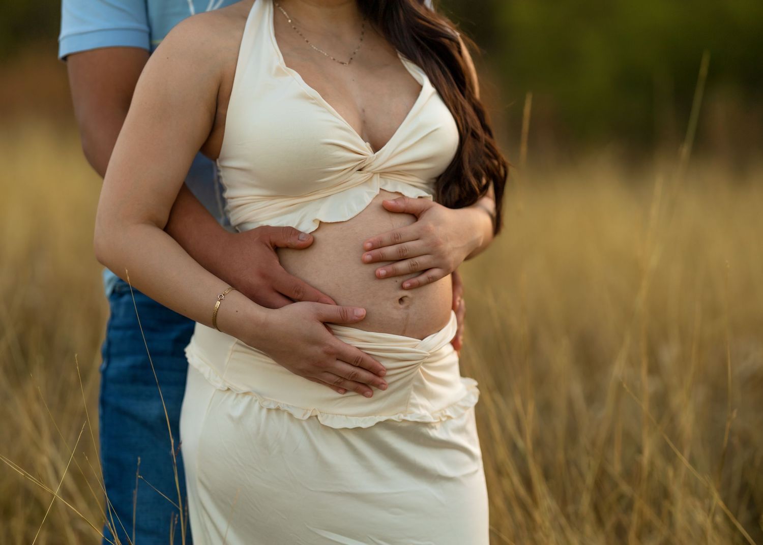 Intimate maternity photoshoot showing white dress and denim in warm natural lighting.