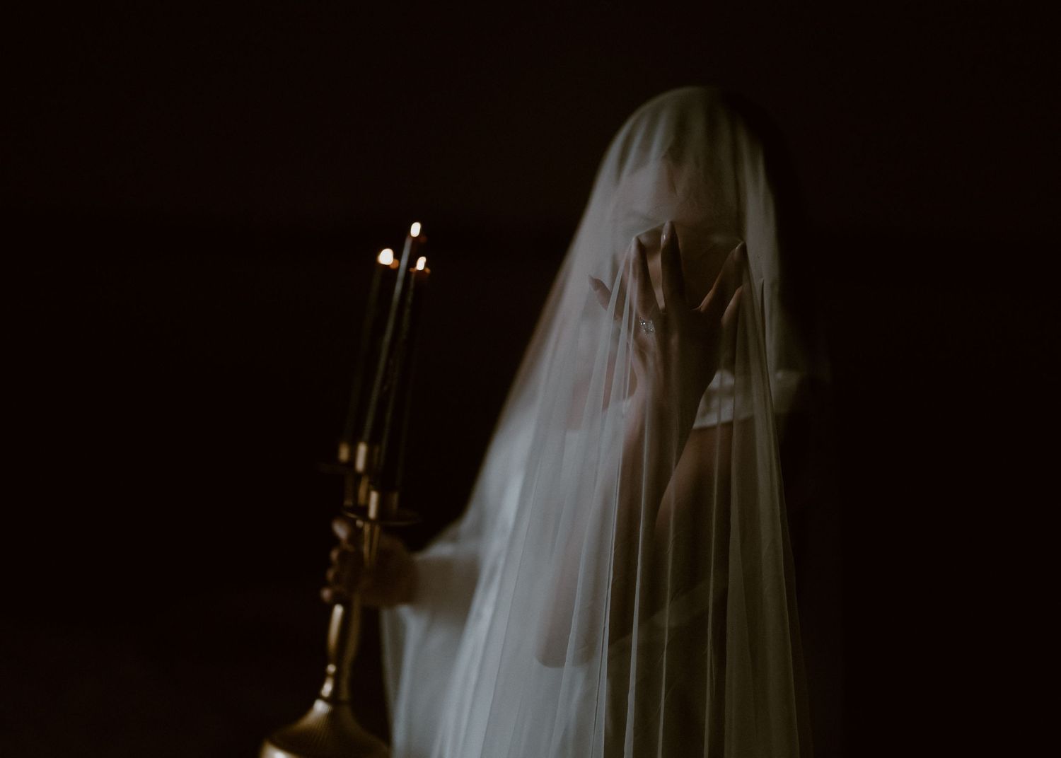 Dark and moody portrait in gothic style with white veil against black background.