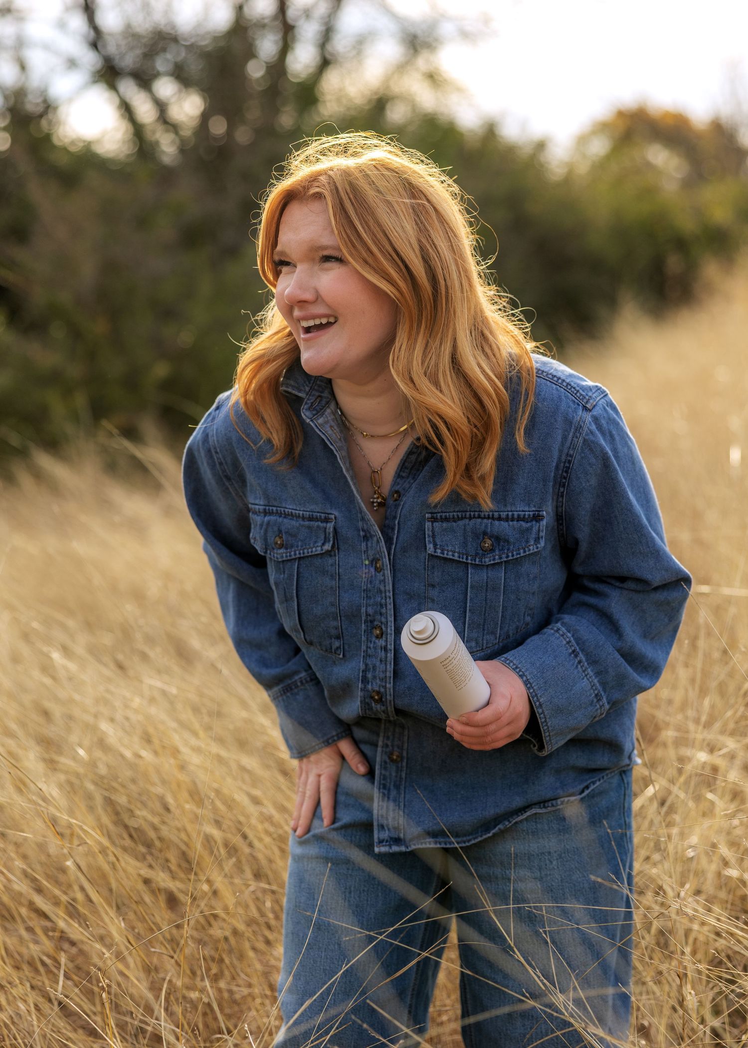 Casual denim outfit photographed in natural grassland setting.
